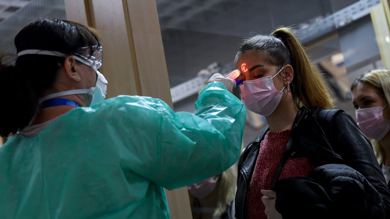 Das Coronavirus reist um die Welt – und damit die Sorge vor einer Pandemie. Hier misst eine Flughafenmitarbeiterin in Debrecen (Ungarn) bei einer Passagierin die Körpertemperatur.