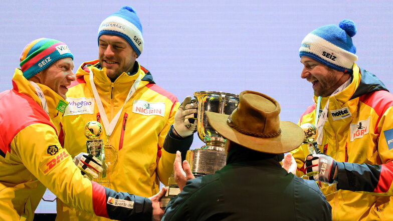 Weltmeister Johannes Lochner (rechts) und sein Anschieber Georg Fleischhauer bekommen den Pokal von Weltverbandspräsident Ivo Ferriani überreicht - unter freundlicher Mithilfe des Rekordsiegers Francesco Friedrich.