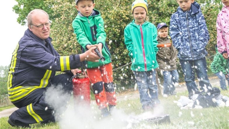 Feuerwehrmann Lehmann zeigt beim Helfertag in Gröditz 2018 den Kids, wie man den Feuerlöscher richtig einsetzt.