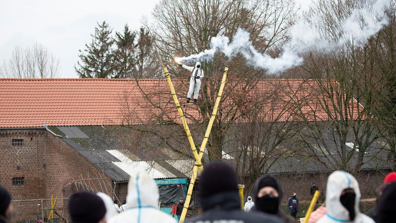 Ein Aktivist steht auf einer Holzkonstruktion und brennt einen Rauchsatz ab.