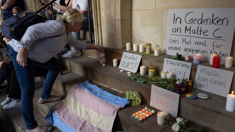 Eine Frau entzündet eine Kerze in Gedenken an Malte C. in Münster. Menschen demonstrieren nach dem Tod eines 25-Jährigen gegen Gewalt an queeren Menschen.