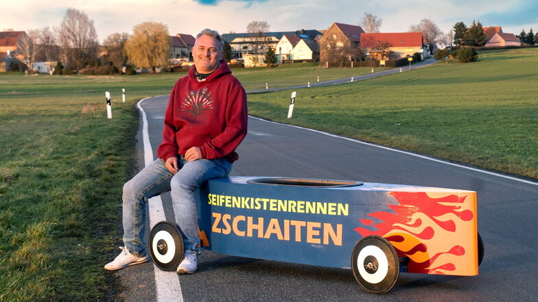 Lutz Hentschel sitzt auf einer Seifenkiste, mit der es auf der Straße von Roda nach Zschaiten (im Hintergrund) hinuntergeht.