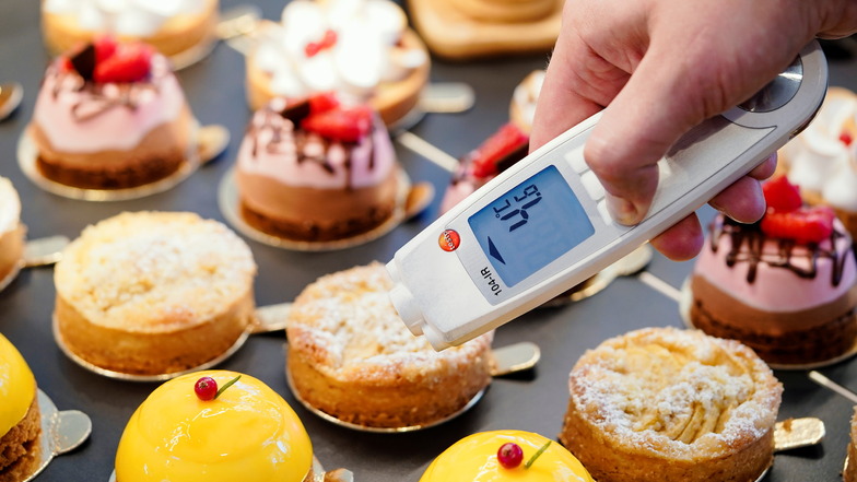 Lebensmittelkontrolle: In einer Patisserie wird die Temperatur an eine kleine Torte in der Kühlauslage gemessen.