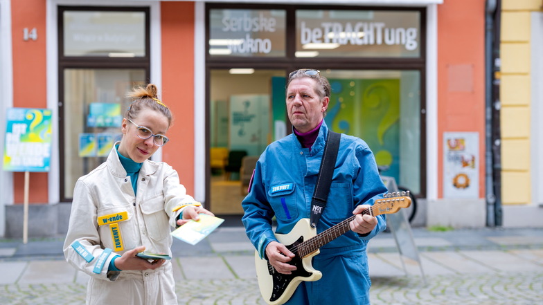 Anna Stiede und Hans Narva locken mit Musik, Flyern und Pflanzen Besucher in die neu eröffnete Ausstellung auf der Reichenstraße.