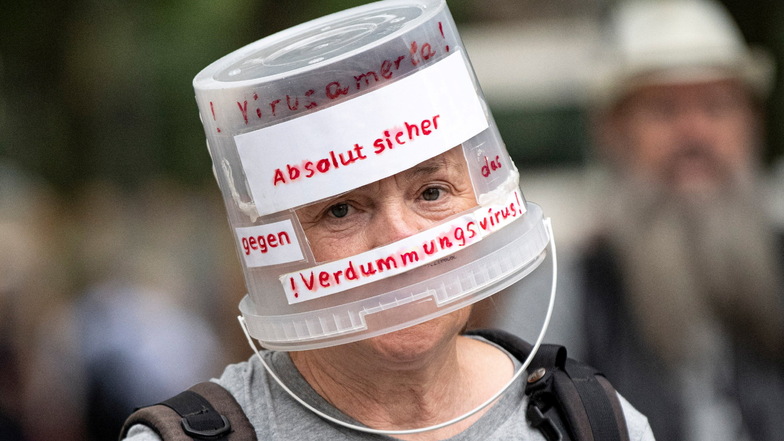 Ein Demonstrant läuft mit einem auf den Kopf gesetzten Plastikeimer bei einer Querdenken-Demo durch Berlin.