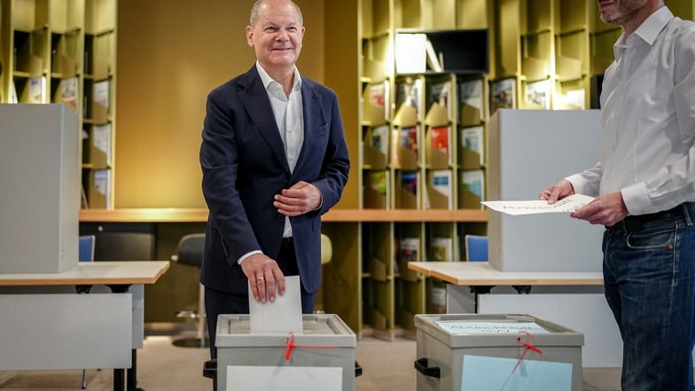 Bundeskanzler Olaf Scholz (l, SPD) gibt seinen Stimmzettel für die Europawahl ab.