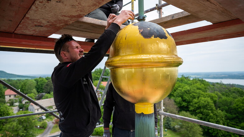 Ein Mitarbeiter einer Görlitzer Dachdeckerei beginnt mit der Demontage der Turmkugel auf dem Kirchturm in Jauernick-Buschbach.