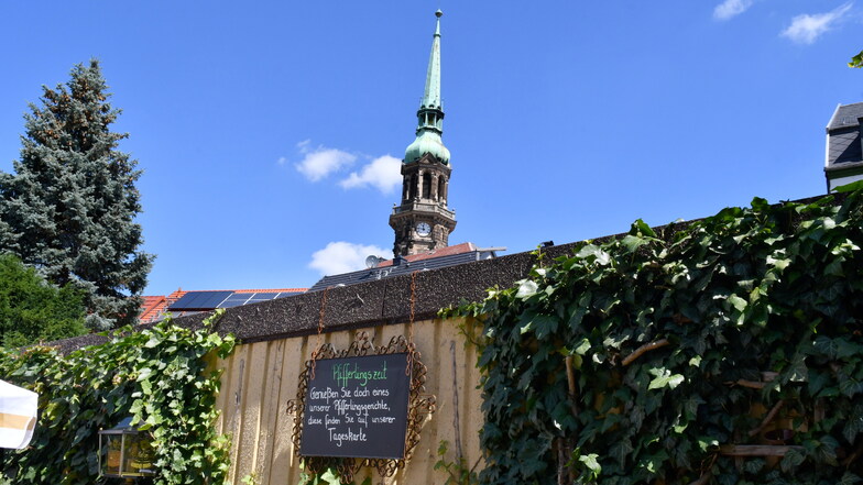 Blick über die Biergartenmauer auf den Turm der Radeberger Stadtkirche.