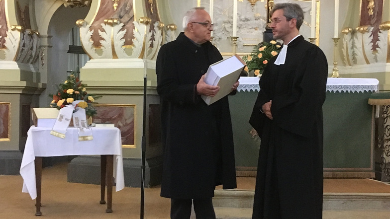 Eckhard Klabunde von der IG Mahnmal (l.) übergibt die Gedenkbücher an Pfarrer Konrad Adolph von der Marienkirchgemeinde zur künftigen Betreuung.