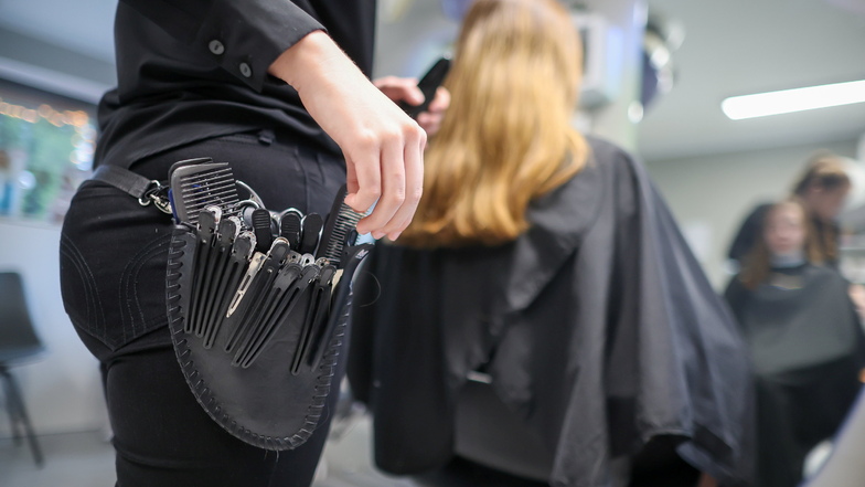 Eine Friseurmeisterin schneidet in einem Salon einer Kundin die Haare. In dieser Branche wie auch in anderen Dienstleistungs-Bereichen dominieren Mini-Löhne.