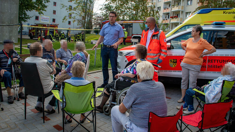Oberbürgermeister Sven Liebhauser spricht zu den geretteten Bewohnern, die auf einem Parkplatz neben dem Haus warten.