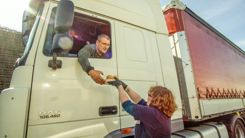 Julia Gornig verteilt Bockwurst und Brötchen an einen Lastwagenfahrer.