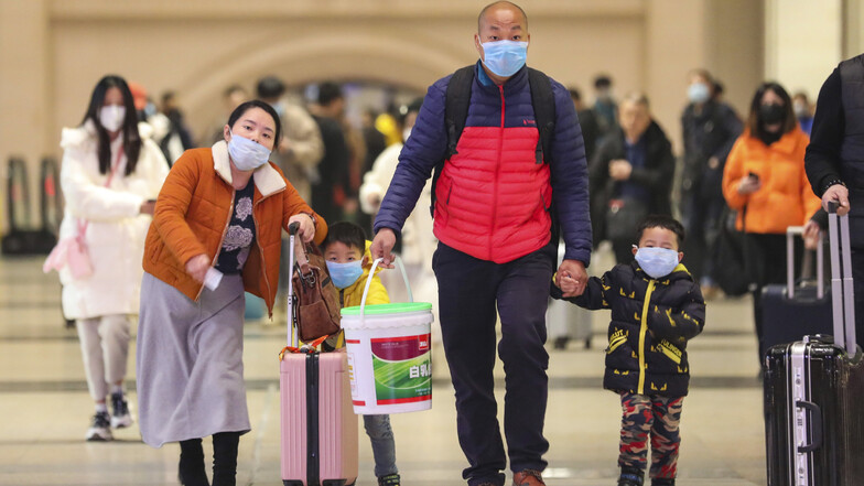 Reisende mit Atemschutzmasken gehen durch den Bahnhof Hankou in Wuhan, wo der Coronavirusausbruch seinen Anfang nahm.