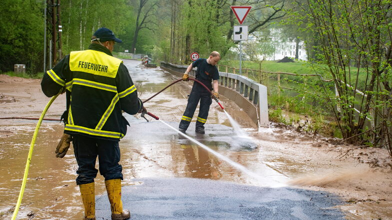 Nach der Überschwemmung in der Nacht beseitigen Harthaer Feuerwehrleute den Schlamm von der Straße in Steina.
