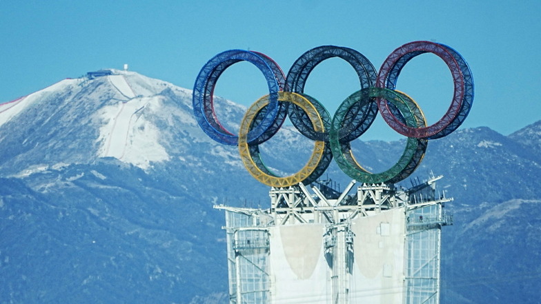 Blick auf die olympischen Ringe auf einem Turm in der Yanqing-Region. Im Hintergrund ist der Start der alpinen Olympia-Abfahrt am Xiaohaituo Mountain im Nationalen Ski-Alpin-Zentrum zu sehen.