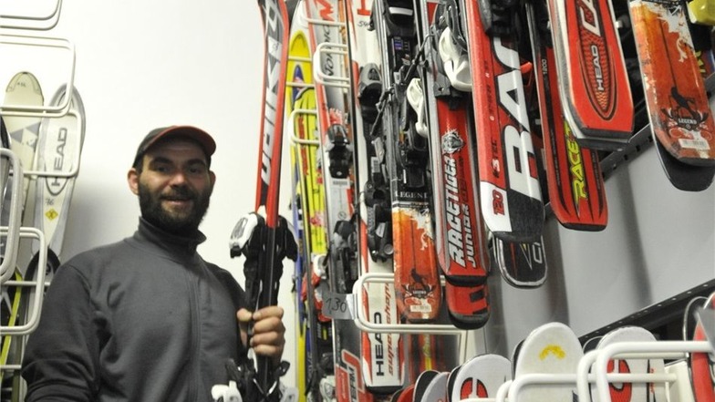 Auf fahrbaren Regalen verstaut Alexander Kind Skier und Snowboards.