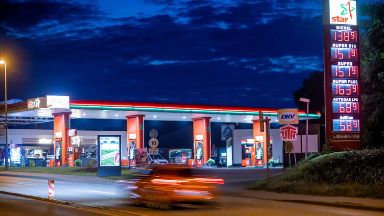 Ein Auto fährt vor Sonnenaufgang an einer beleuchteten Tankstelle vorbei. Die Spritpreise sind zuletzt stark gestiegen.