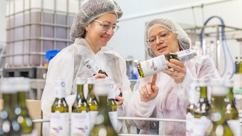 Andrea Sippel und Antje Steglich begutachten die Etiketten der Mehrwegflaschen in der Produktion.