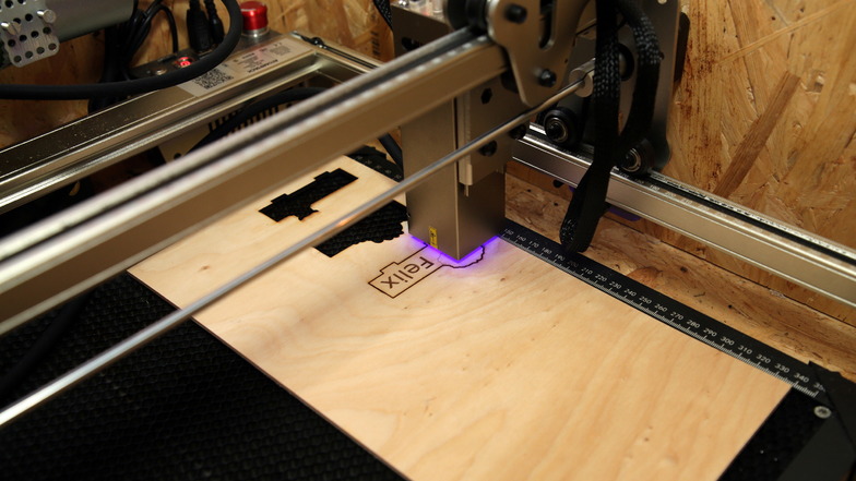 Grelles, violettes Licht zeigt die Stelle, an der sich der Laser ins und durchs Holz frisst - Millimeter für Millimeter, bis das Namensschild fertig ist.