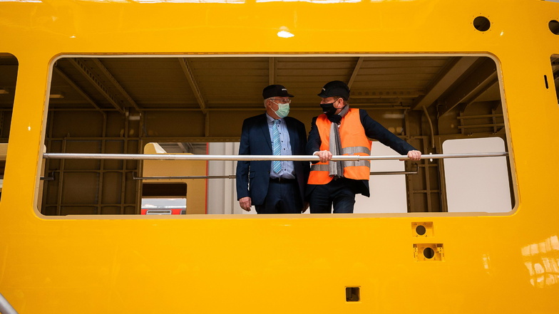 Carsten Liebig, Leiter des Bombardier Werkes Görlitz, und Ministerpräsident Michael Kretschmer (rechts) fachsimpeln im Rohbau der neuen Straßenbahn für Dresden.