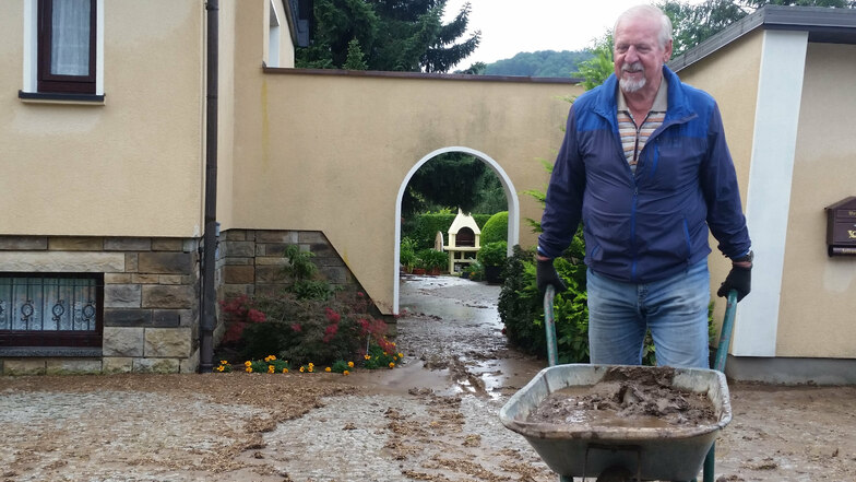 Großreinemachen nach der Überflutung am Montagmorgen: Gernot Fünfstück karrt Schlamm von seinem Grundstück am Langen Garten in Oberoderwitz.