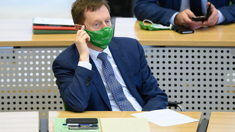 Michael Kretschmer sitzt während der Debatte im Plenum mit Maske auf seinem Platz im Landtag.