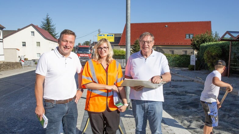 Der Laußnitzer Bürgermeister  Rene Georgi, Urte Wappler vom Landesamt für Straßenbau und Verkehr und Planer Peter Linke (v.l.) begutachten den ersten Abschnitt der ausgebauten Schulstraße. Ab Montag ist der nächste Abschnitt an der Reihe.