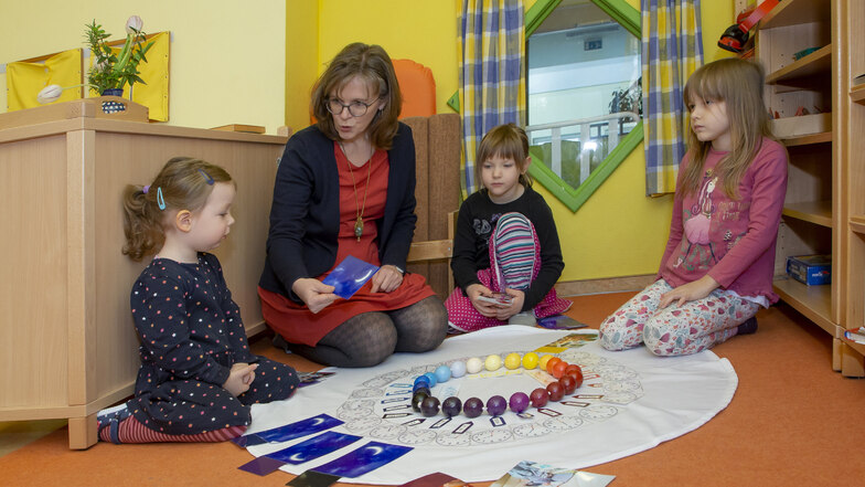 Leiterin Jana Grünert beschäftigt sich im Tageskreis der Kita Samenkorn mit den Kindern Greta (2), Svea (5) und Anna-Maria (5).