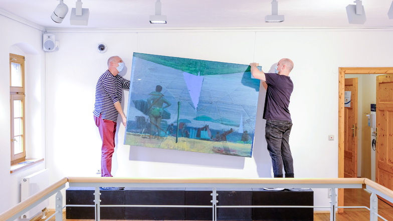 Der Aufbau für die neue Ausstellung ist im vollen Gange. Künstler Christian Manss (r.) hängt mit Stadtgalerist Alexander Lange eines seiner Bilder auf.