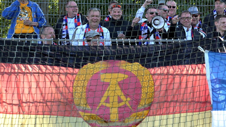 Mit der Fahne der untergegangenen DDR unterstützen Fans eine Auswahl ehemaliger Fußballer in Emden, doch Ostfriesland ist stärker.