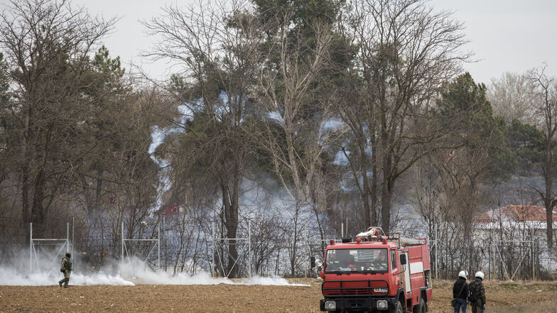 Griechische Sicherheitskräfte stehen am Grenzzaun zur Türkei in dessen Nähe Tränengasgranaten abgefeuert werden.