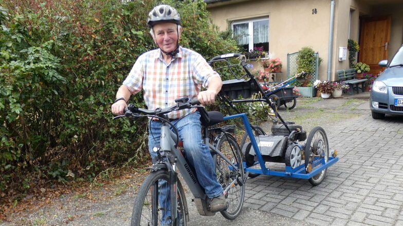 Arnulf Sachße, wie ihn die Neschwitzer kennen: Mit Fahrrad und Rasenmäher auf dem Anhänger ist er unterwegs, um die Wanderwege von Bewuchs zu befreien.