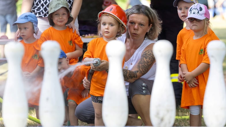 Lotta bringt zusammen mit Romy Stephan vom Kinderhaus "Am Bobersberg" bei der Jugendfeuerwehr Großenhain Kegel von einem Tisch per Wasserstrahl. Das war eines von vielen Angeboten bei der Spielplatzparty am Mittwoch im Stadtpark.