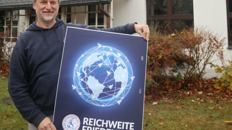 Jörg Michel ist Pfarrer der Evangelischen Kirchengemeinde Hoyerswerda-Neustadt. Vor dem Martin-Luther-King-Haus zeigt er ein Plakat mit dem Leitmotiv der diesjährigen FriedensDekade.