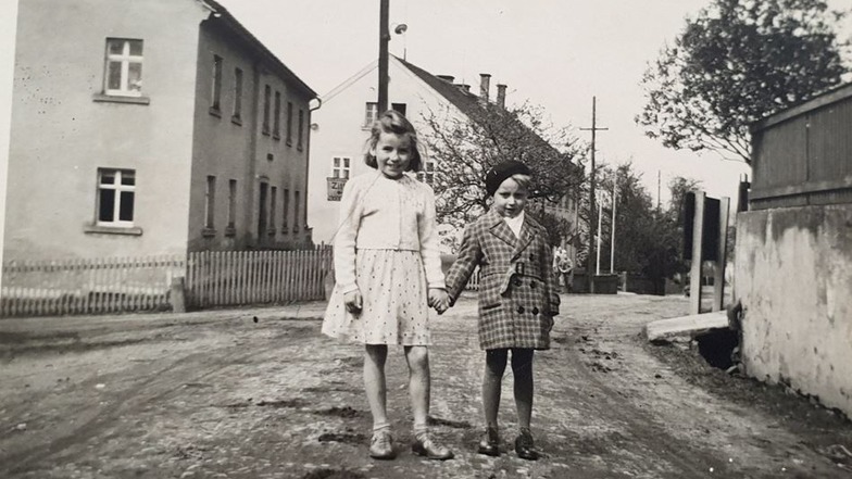 Das Bild zeigt Erika Brückner – geborene Paul – als Neunjährige mit einer Freundin in Oberullersdorf vor der Bäckerei. Das Haus dahinter ist die Schule.