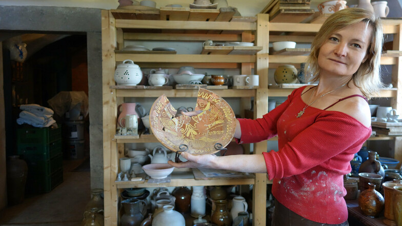 Magdalena Brožová zeigt einen in Engobe-Keramik gefertigten historischen Teller aus Lewiner Geschirr. Die Keramikerin hat die jahrhundertelange Tradition neu belebt.