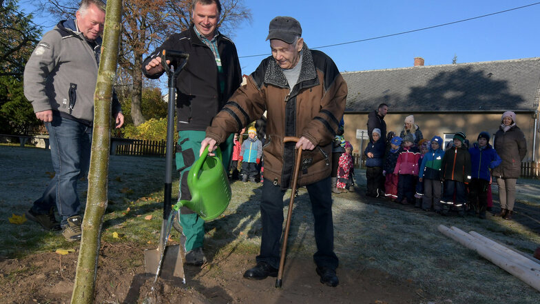 Kurt Schneider versorgt den frisch gepflanzten Baum mit Wasser. Der 100-Jährige wohnt seit seiner Geburt in dem Dorf.