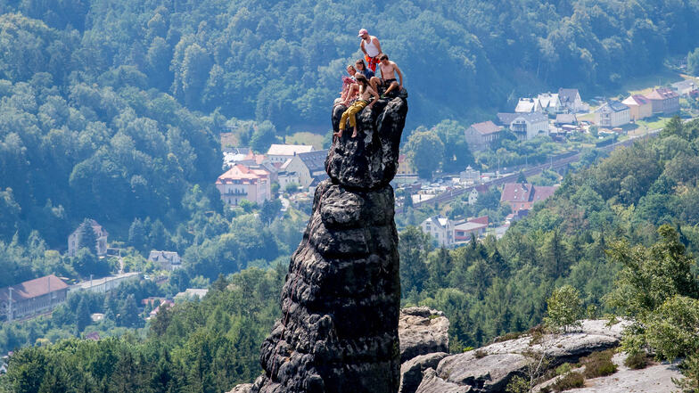 Kletterer sitzen auf der Schrammsteinnadel und schauen ins Elbland hinab.