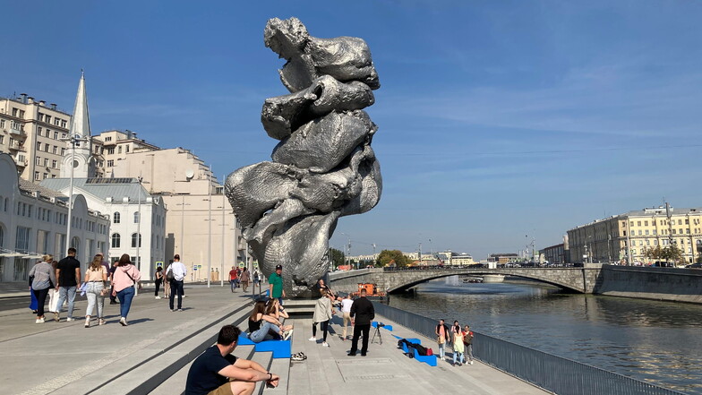 Menschen sitzen neben der Skulptur ·Big Clay #4· des Schweizer Künstlers Urs Fischer in Moskau. (