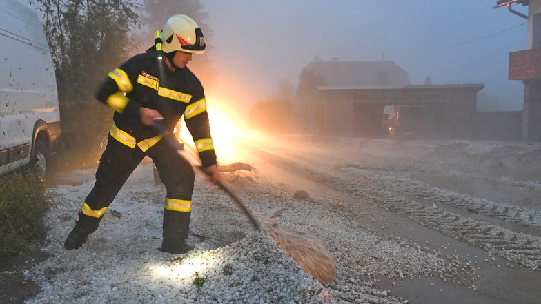 Österreich, Pinsdorf: Feuerwehrleute räumt Hagel zur Seite. In Österreich haben Unwetter mit großen Hagelkörnern zahlreiche Gebäude und Autos beschädigt.