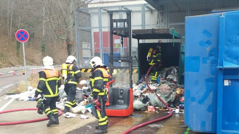 Feuerwehrleute der Freiwilligen Feuerwehr Meißen löschen den schwelenden Müll in der Müllpresse am Kaufland an der Schützestraße. Ein Elektrostapler hält die Klappe offen.