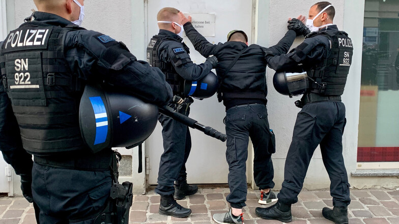 Polizisten halten einen Mann in Pirna fest, nachdem es dort bei einer Corona-Demo zu Gewalttätigkeiten gegen die Beamten kam.