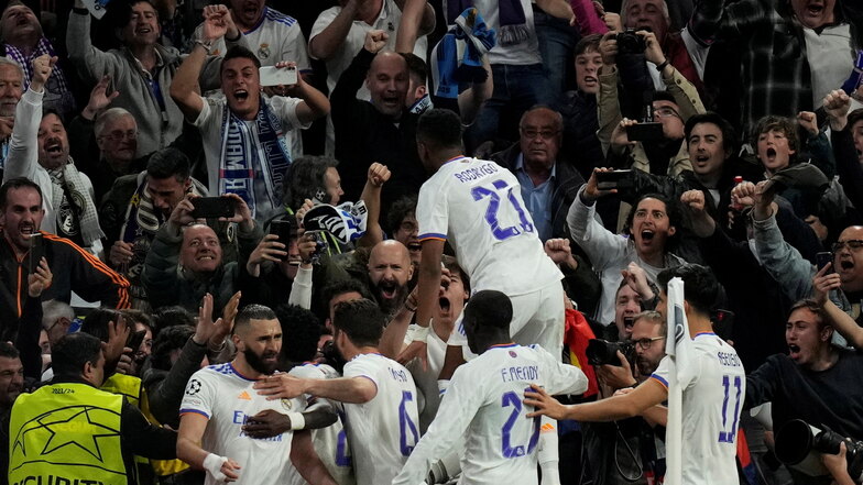 Karim Benzema (links) von Real Madrid feiert mit Teamkollegen und Fans das dritte Tor seiner Mannschaft.