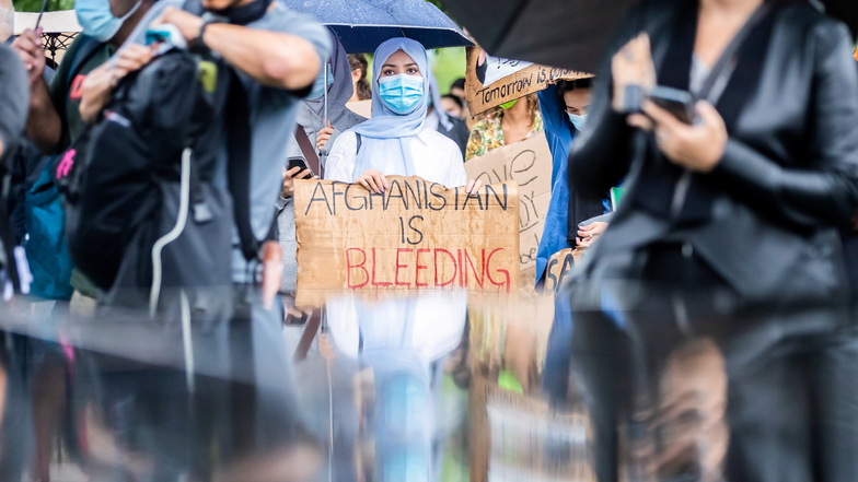 Eine Demo-Teilnehmerin hält vor dem Bundeskanzleramt in Berlin ein Schild mit der Aufschrift "Afghanistan is bleeding" (Afghanistan blutet).