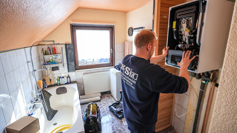Ein Mitarbeiter Heizungsbauer installiert eine  Gasbrennwerttherme in einem Einfamilienhaus.