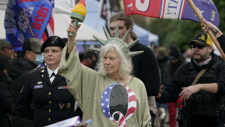Eine Person, die als Lady Liberty gekleidet ist, trägt ein Hemd mit dem Buchstaben Q, der sich auf QAnon bezieht, als Demonstranten an einem Protest teilnehmen, am Kapitol in Olympia, Wash. Die Demonstranten protestierten gegen die Auszählung der Wahlmänn
