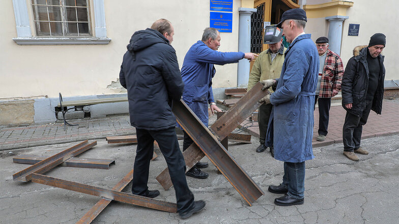 Während Frauen und Kinder die Stadt Lwiw verlassen, bauen einige Männer Hindernisse aus "Tschechenigel" in Vorbereitung eines möglichen russischen Angriffes.