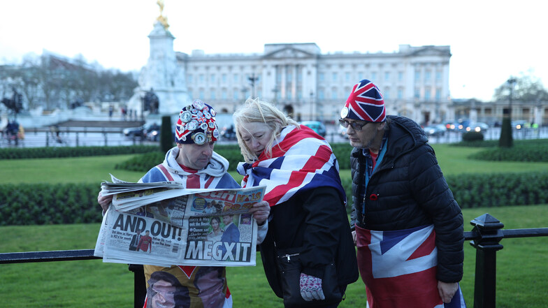 Fans lesen die Tagezeitung "The Sun"  vor dem Buckingham Palace, nachdem bekannt wurde, dass Prinz Harry und Herzogin Meghan teilweise von ihren royalen Verpflichtungen zurücktreten.