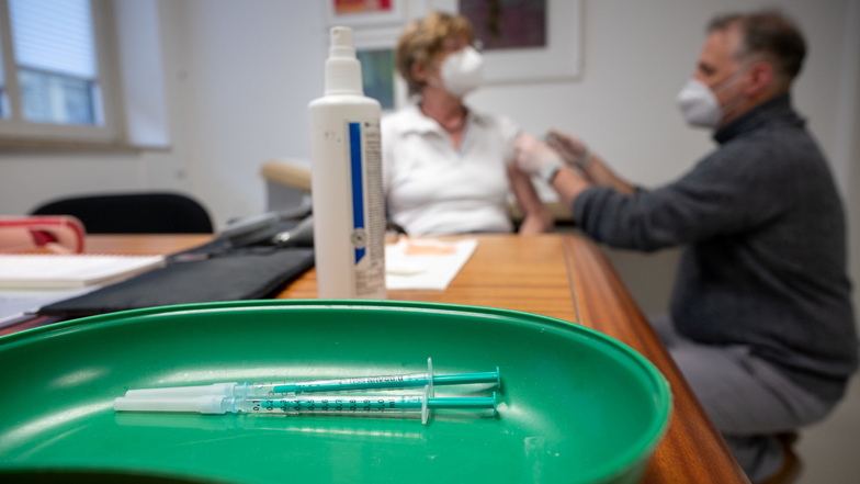 Ein Arzt impft in einer Praxis gegen das Coronavirus: Impfwilige müssen Geduld aufbringen - auch in Sachsen .
