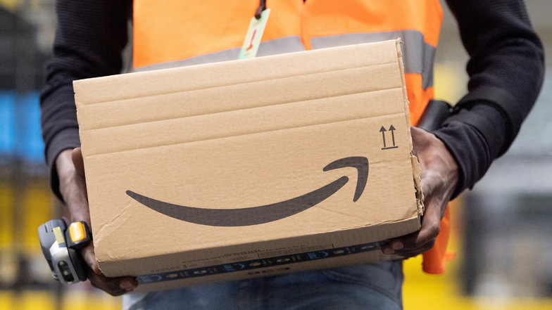 Ein Mitarbeiter von Amazon trägt ein Paket.